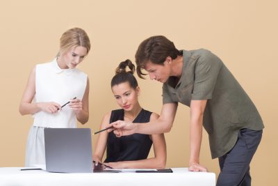 3 jüngere Menschen reden vor dem Laptop