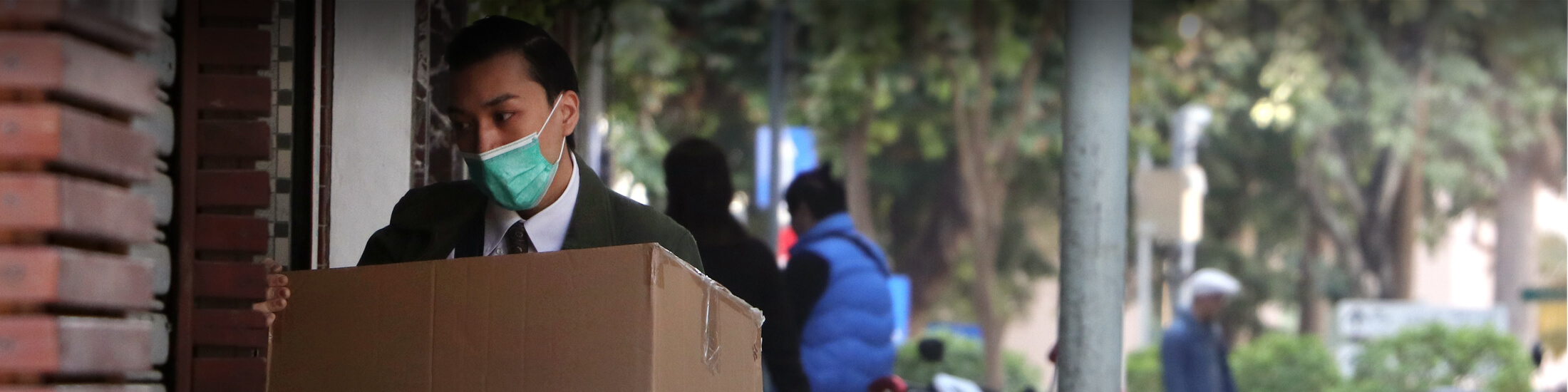 Mann mit einem Mundschutz, trägt eine Kiste.