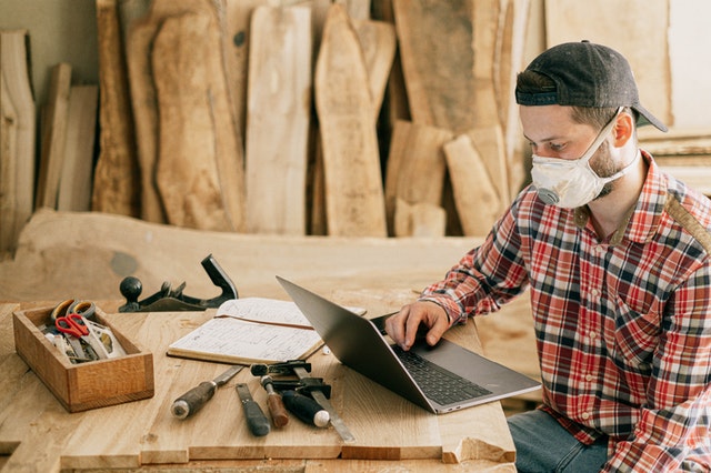 Handwerker mit einer Maske und einem Laptop