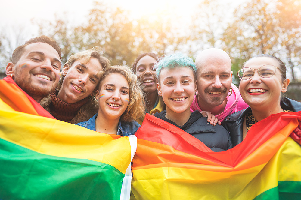 Multiracial Menschen halten eine Regenbogenflagge LGBT und laecheln